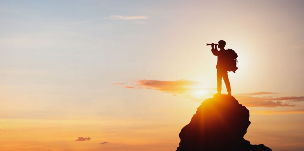 vision for success ideas. businessman's perspective for future planning. Silhouette of man holding binoculars on mountain peak against bright sunlight sky background.
